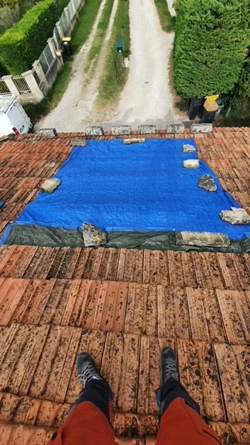 Bâche bleue posée sur un toit pour stopper une fuite