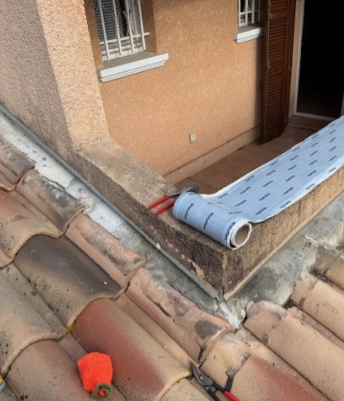 Installation et ajustement précis du solin entre le mur de façade et les tuiles romanes